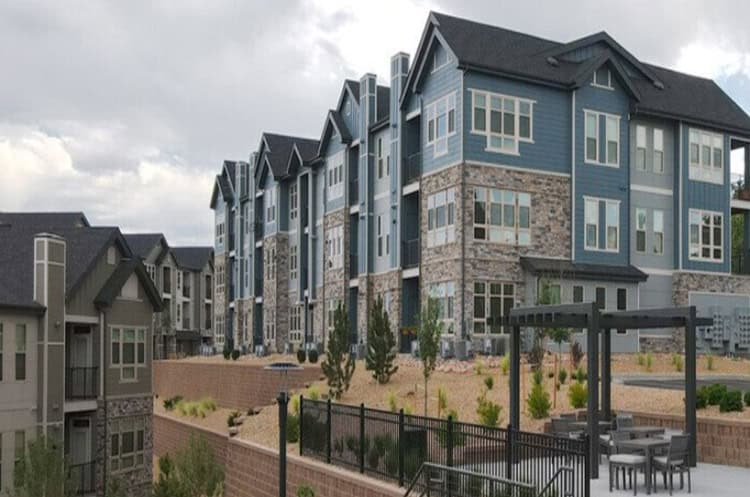 Modern multi-story apartment complex with stone and blue siding, landscaped outdoor spaces at Hibernia Housing.